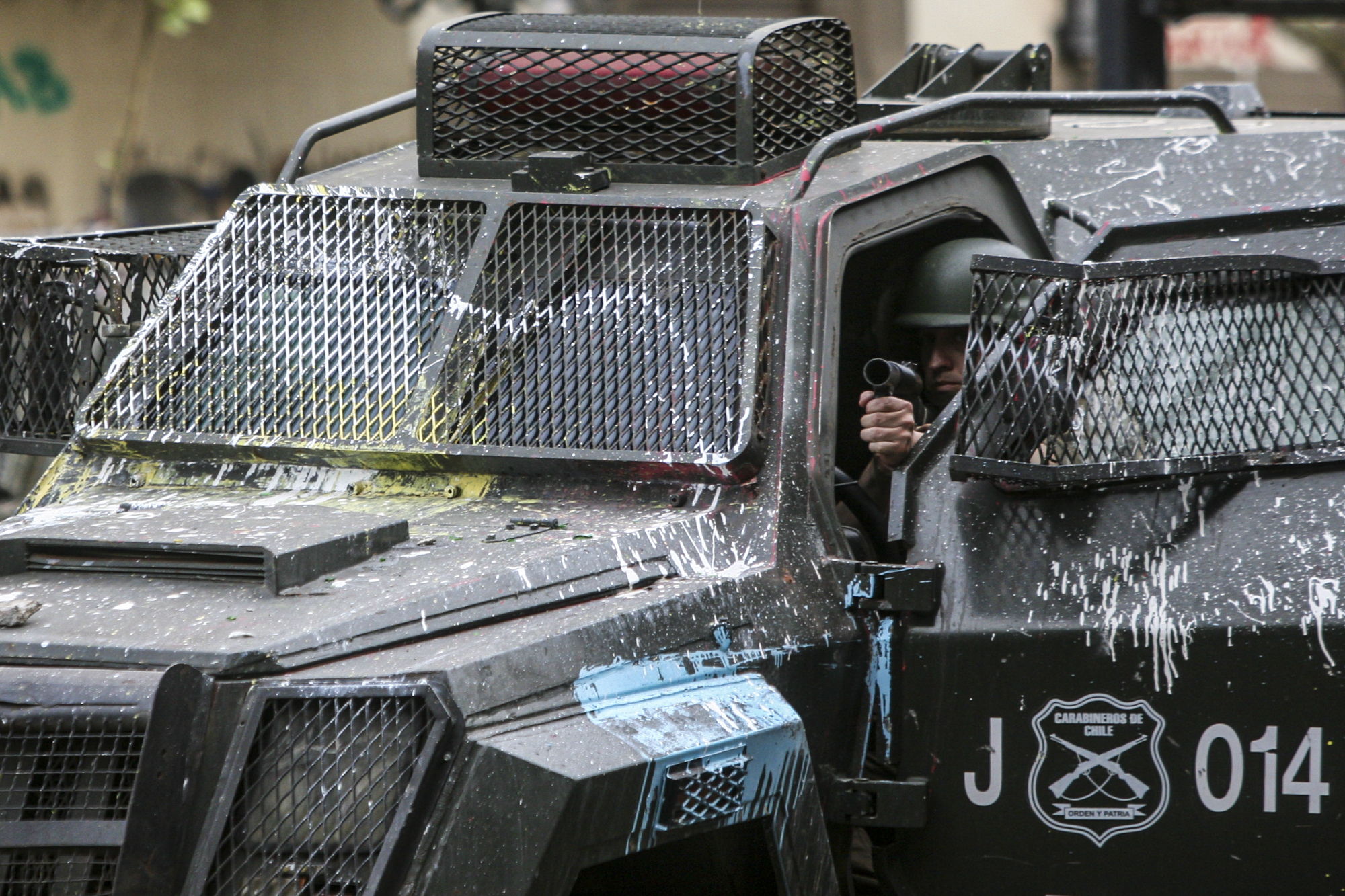 04 de noviembre 2019. Un funcionario de Fuerzas Especiales de Carabineros apunta un lanza lacrimógenas mientras se cubre al interior de un carro lanza gases. 04 de noviembre 2019. Un funcionario de Fuerzas Especiales de Carabineros apunta un lanza lacrimógenas mientras se cubre al interior de un carro lanza gases.