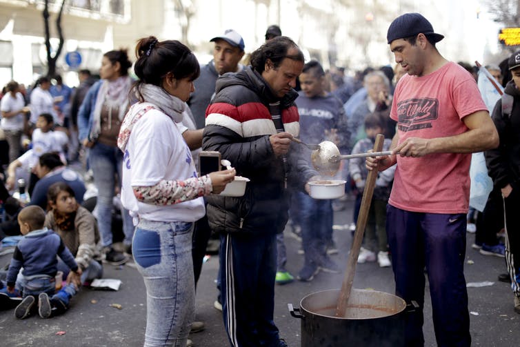 Un hombre sirve comida a las puertas de un comedor social de la avenida principal. AP Photo/Natacha Pisarenko Un hombre sirve comida a las puertas de un comedor social de la avenida principal. AP Photo/Natacha Pisarenko