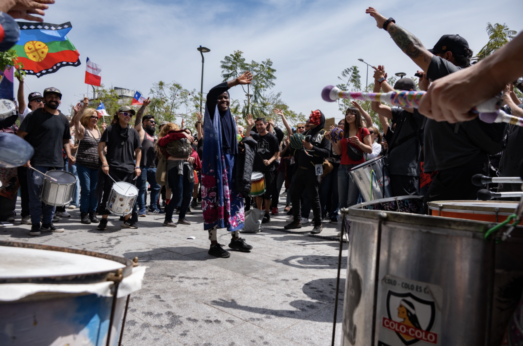 Una mujer baila en un círculo de tambores, cantando “chúpalo, Kast” con el toque de tambor afuera del metro Baquedano. (Foto: Ike Wood / Interferencia.cl)