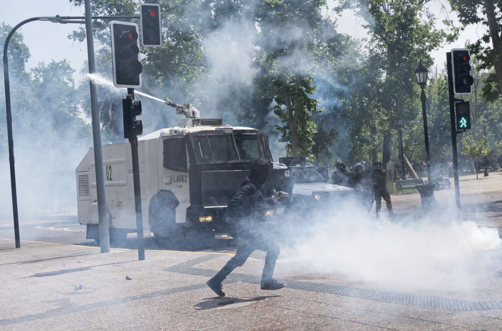 Un manifestante navega el fuego de agua y gas mientras el avance de los carabineros para Plaza Baquedano. (Foto: Ike Wood / Interferencia.cl)