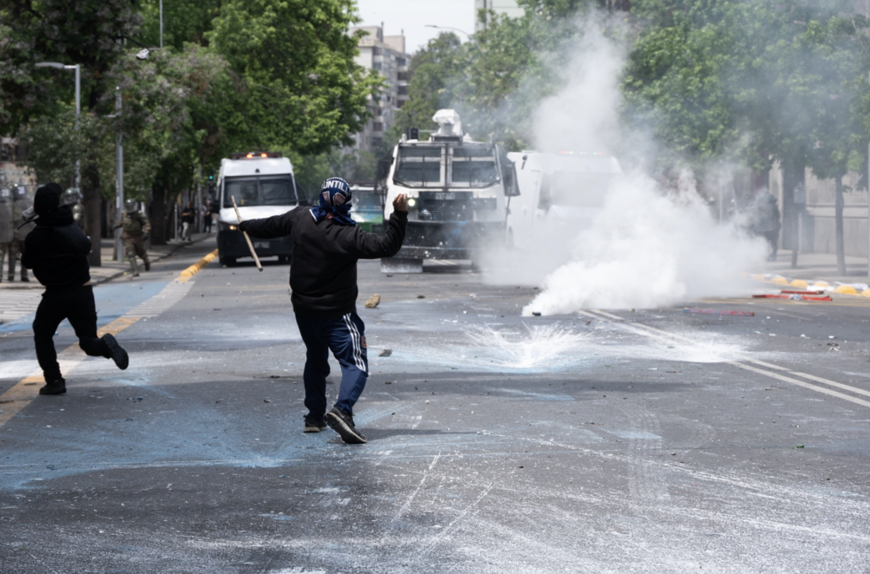 Un manifestante tira una piedra a los vehículos de los carabineros en Av. Portugal. (Foto: Ike Wood / Interferencia.cl)