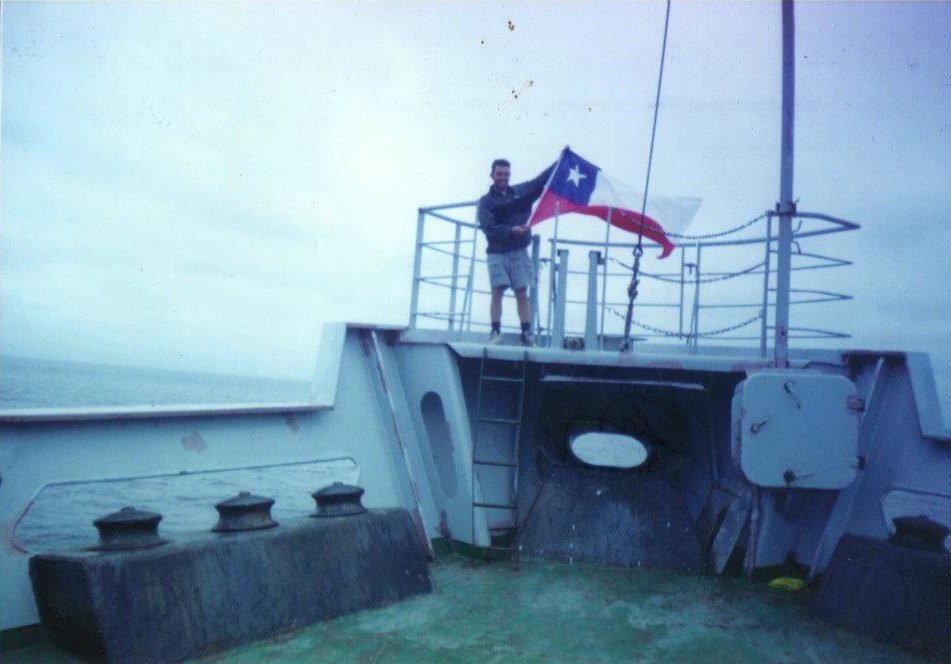 Lun Lee sostiene una bandera chilena que ondea con el viento del océano pacífico en altamar.