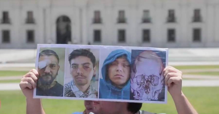 Un manifestante muestra una imagen de los heridos frente a La Moneda en la marcha de la Coordinadora de Víctimas de Traumas Oculares. 