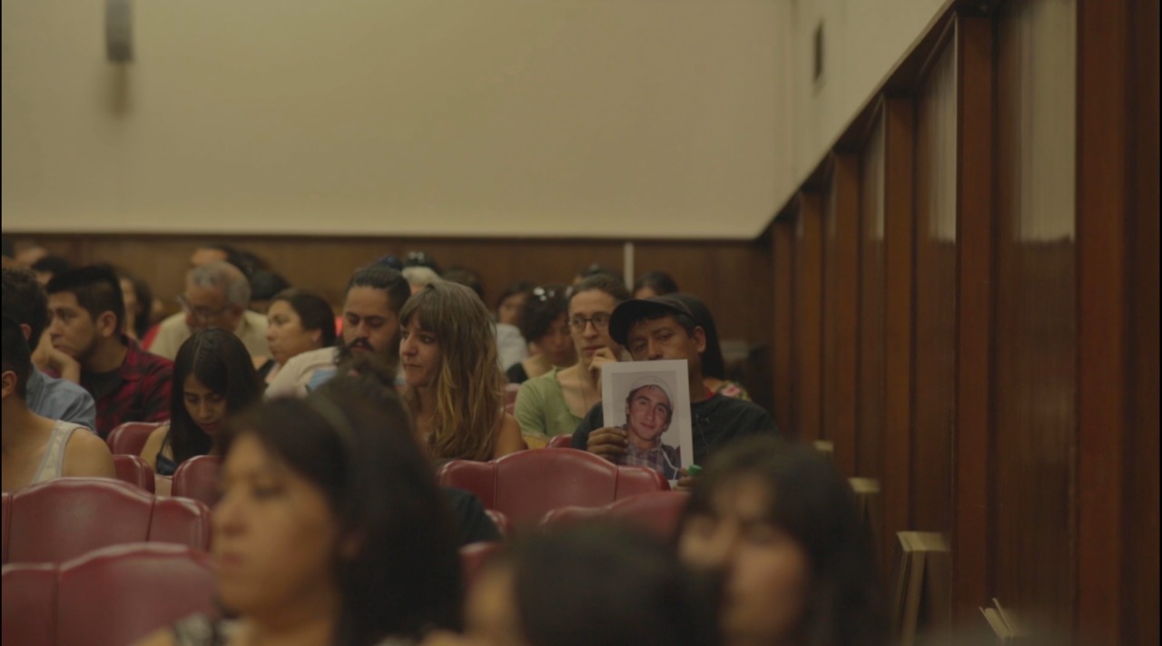 Manuel Rebolledo Ibacache sosteniendo una foto de su hijo durante una visita de la Comisión Interamericana de Derechos Humanos a Concepción - Crédito: Isidora Melo Ramírez, directora de fotografía del documental.